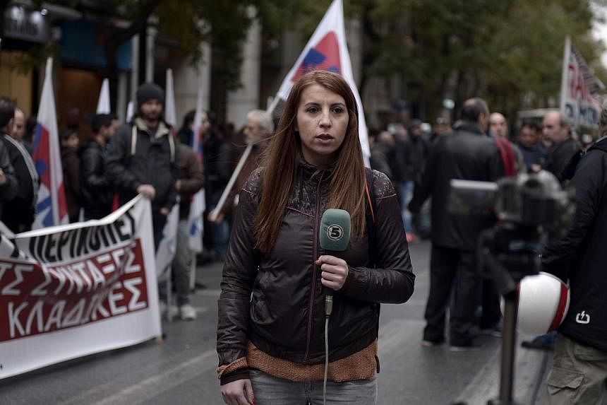 A foreign journalist reports on a media strike during a rally outside the journalists union in central Athens on Nov 26, 2014. Greek journalists went on a 24-hour strike shutting radio and TV broadcasts ahead of the general strike on Nov 27th. -- PHO