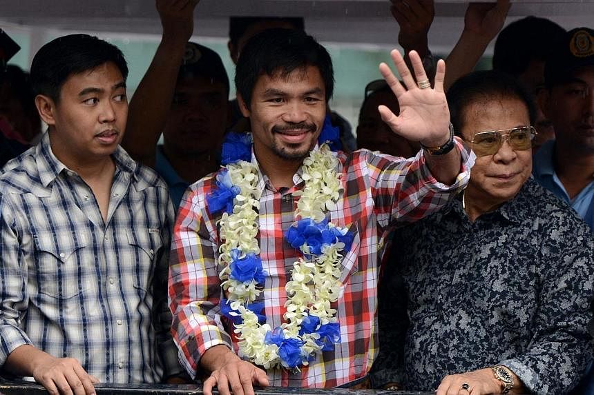 Philippine boxing champion Manny Pacquiao (centre) waves to his fans during his victory parade in Manila on Nov 27, 2014. -- PHOTO: AFP