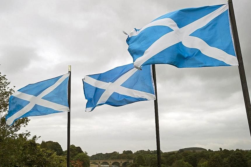 A file picture taken on Sept 16, 2014, shows Scottish Saltire flags flying above the River Tweed in the town of Coldstream on the border between England and Scotland. -- PHOTO: AFP