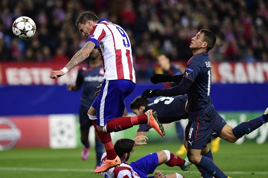 Atletico Madrid's Croatian forward Mario Mandzukic (left) heads the ball to score during the UEFA Champions League Group A football match against Olympiakos FC at the Vicente Calderon stadium in Madrid on Nov 26, 2014. -- PHOTO: AFP