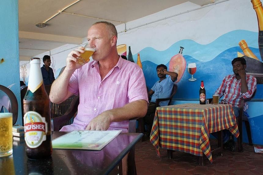 British tourist John Packer, a 41-year-old tiler, drinks a beer at a seafront restaurant in the resort town of Kovalam, in southern Kerala state on Sept 9, 2014.&nbsp;Tourists travelling to India from 43 countries including the US will no longer have