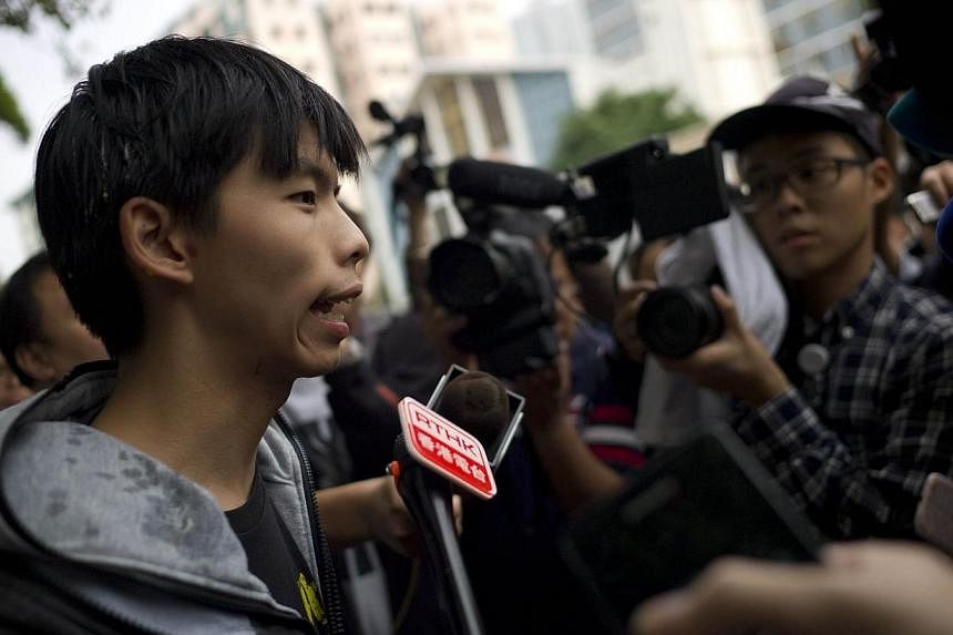 Student leader Joshua Wong (left) speaks with reporters after he was hit with an egg near a courthouse following his release on bail in Hong Kong on Nov 27, 2014.&nbsp;-- PHOTO: AFP
