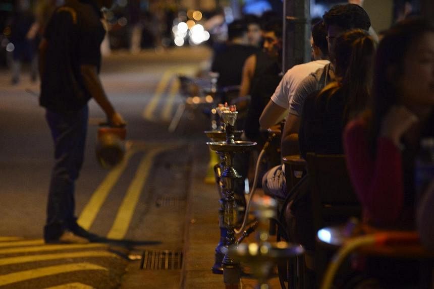A customer smokes a shisha or "hookah" pipe at a cafe on Bussorah St on Nov 4, 2014.&nbsp;The importation, distribution and sale of shisha tobacco will be illegal in Singapore as of Friday. -- ST PHOTO: MARK CHEONG
