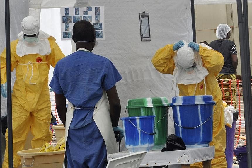 A Doctors Without Borders health worker takes off his protective gear under the surveillance of a colleague at a treatment facility for Ebola victims in Monrovia Sept 29, 2014.&nbsp;&nbsp;The European Commission called on Wednesday for 5,000 doctors 