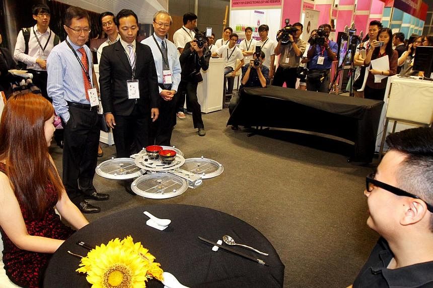 Visitors watching a flying robot waiter in action at the launch of National Productivity Month on Oct 7, 2014.&nbsp;-- PHOTO: LIANHE ZAOBAO