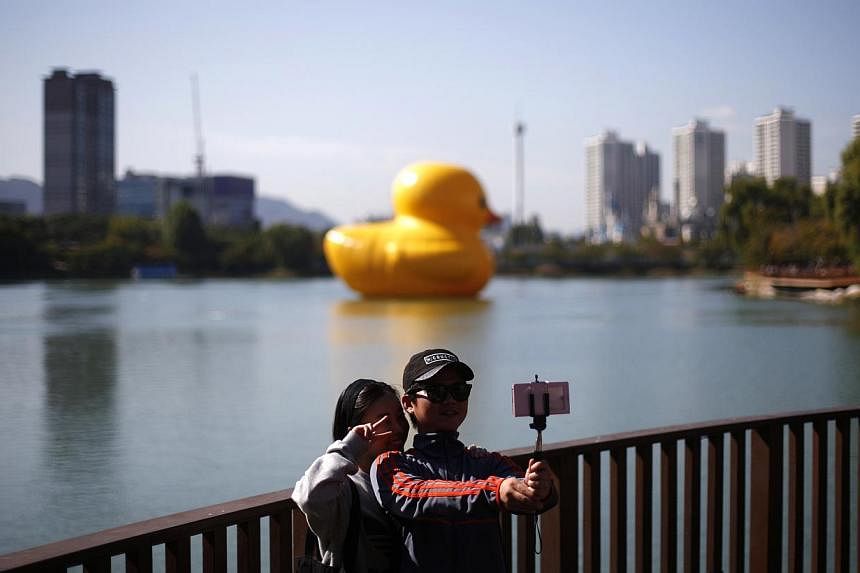 A couple takes a "selfie" in front of the giant inflatable Rubber Duck installation floating in Seokchon Lake in Seoul on Oct 14, 2014. -- PHOTO: REUTERS