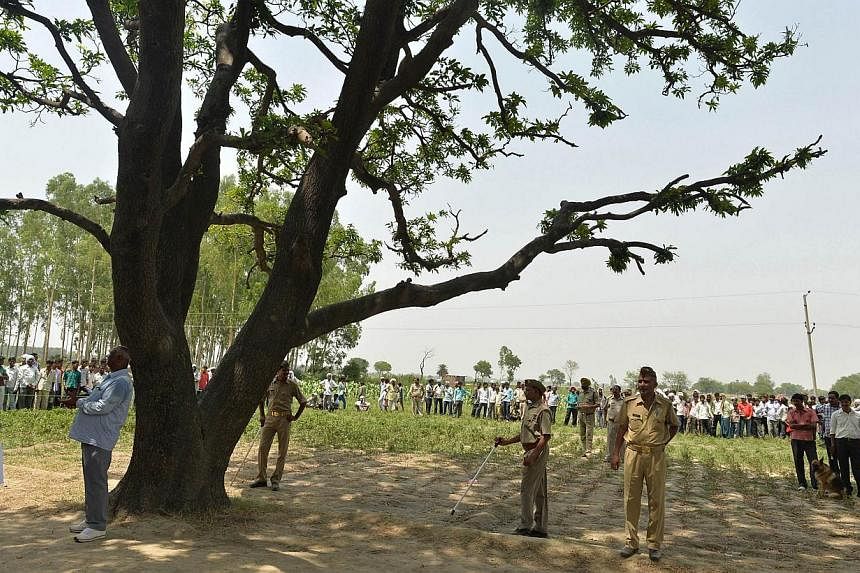 In this photograph taken on May 31, 2014, Indian police officials keep watch at the tree where the bodies of two girls were found hanging in Katra Shahadatgunj in Badaun district, in the northern Indian state of Uttar Pradesh. -- PHOTO: AFP