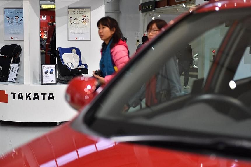 Visitors look at displays of Japanese auto parts maker Takata (left) at a car showroom in Tokyo on Nov 11, 2014.&nbsp;US regulators on Wednesday pressured Japanese auto parts maker Takata to expand its recall of potentially defective airbags across t