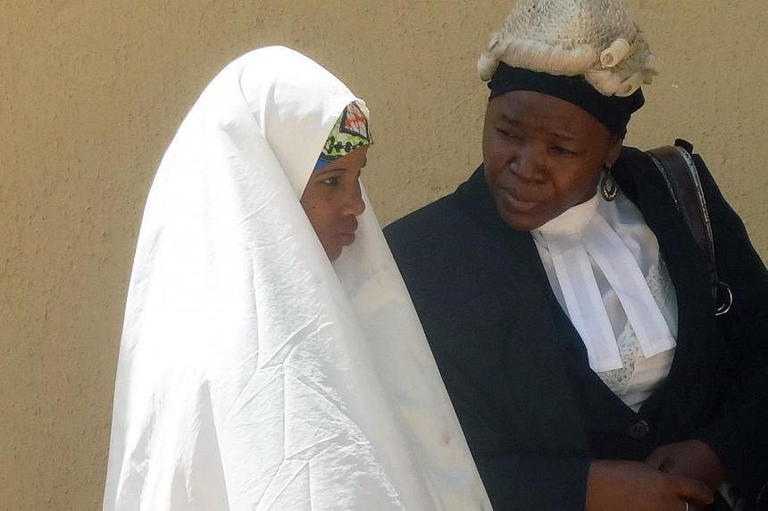 Wasila Tasi'u, 14, speaks with an unidentified defence counsel during a 30-minute break on the first day of her trial at Kano state high court in the village of Gezawa outside Kano on Oct 30, 2014. Tasi'u is&nbsp;accused of murdering her 35-year-old 