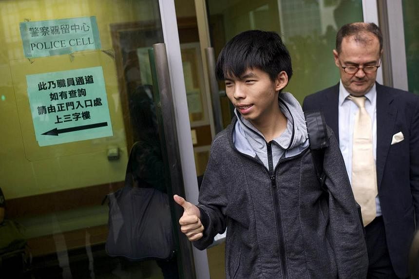 Student leader Joshua Wong (centre) gives a thumbs up as he exits a courthouse with his lawyer Michael Vidler after Wong was released on bail in Hong Kong on November 27, 2014. A court in the semi-autonomous city banned the pro-democracy leader from 