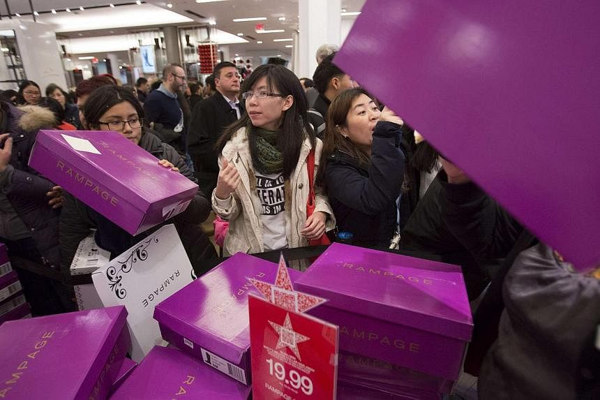 People sorting through boxes of shoes in Macy's in New York on Nov 27, 2014. Singaporeans can join in the shopping frenzy online as e-tailers cash in on the post-Thanksgiving tradition by offering deep discounts over the weekend. -- PHOTO: REUTERS