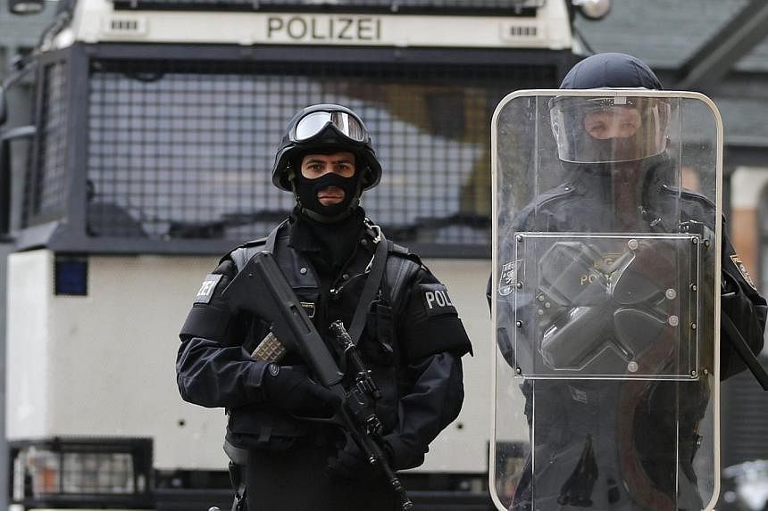 Austrian police officers in full combat adjustment for life threatening mission including gun (not used for riots in Austria) (left) and uniform of riot police officer (right) pose in front of a water cannon at their headquarters in Vienna on Oct 8, 