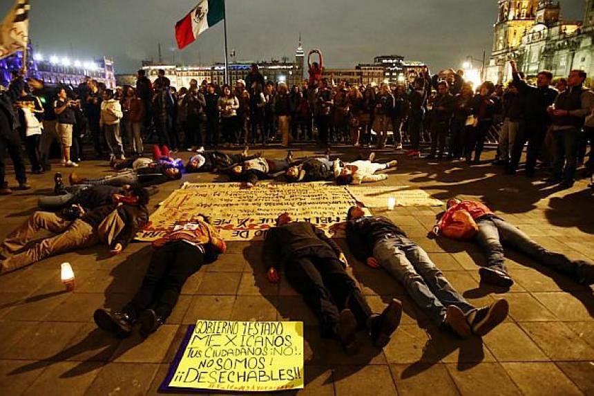 People lie in a circle pretending to be dead near the ceremonial palace of Mexican President Enrique Pena Nieto during a protest denouncing the apparent massacre of 43 trainee teachers in Mexico City late Nov 8, 2014.&nbsp;Eleven beheaded bodies were