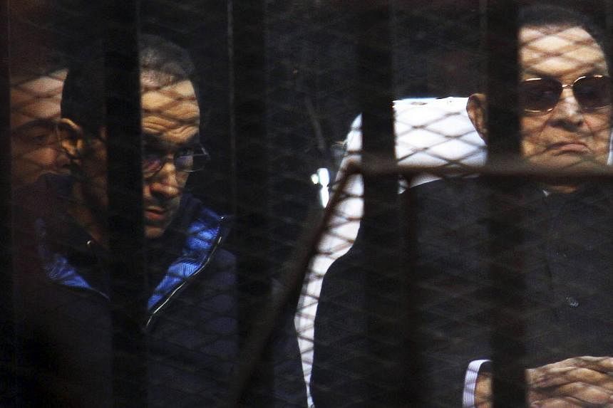 Former Egyptian President Hosni Mubarak listens next to his son Gamal (left) inside a dock during his trial at the police academy on the outskirts of Cairo on Nov 29, 2014. Mubarak said Saturday he "did nothing wrong", after a court dismissed a murde