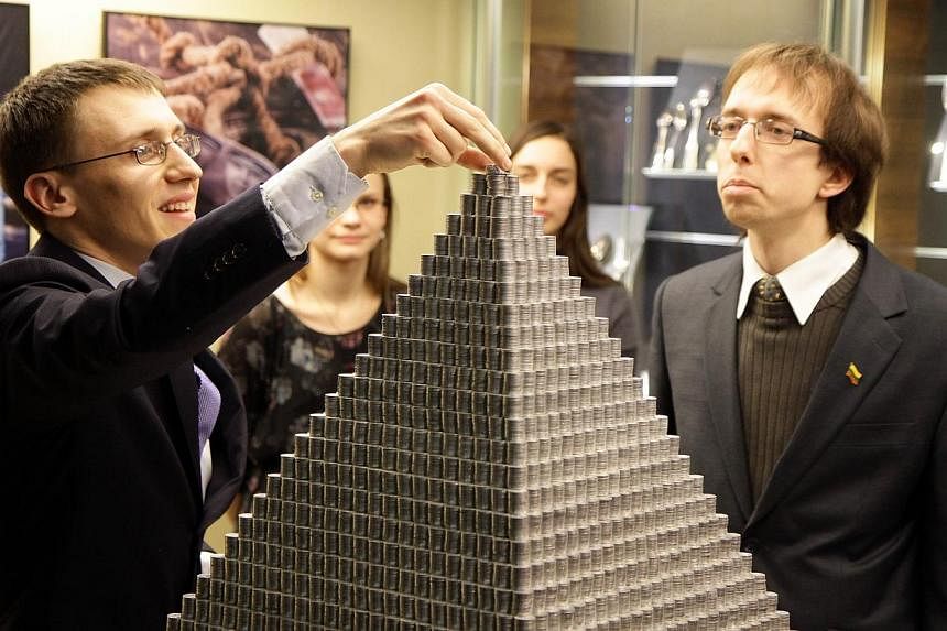 A man puts finishing touches to a pyramid made of 1,000,935 Lithuanian cents on Nov 29, 2014 in Vilnius, Lithuania.&nbsp;The Baltic nation of Lithuania on Saturday unveiled what it billed as the world's largest-ever coin pyramid ahead of its switch f