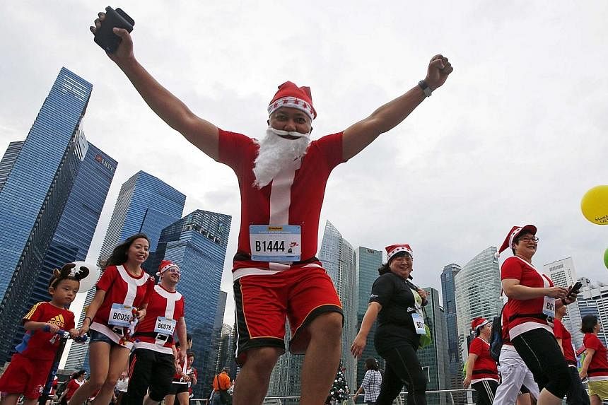 A participant reacts to the camera as they start the Santa Run for Wishes charity run along the Marina Promenade in Singapore's central business district on Nov 29, 2014.&nbsp;Singapore's first Santa-themed run saw some 4,600 runners take to the Mari