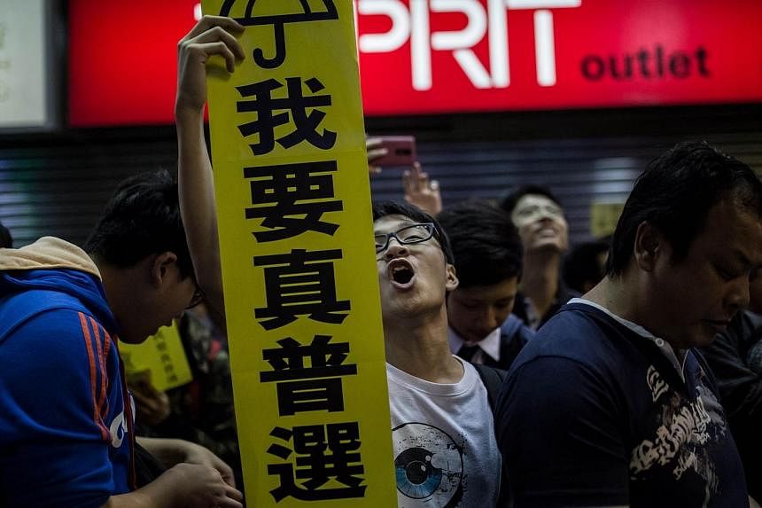 A pro-democracy protester (centre) holds a sign for the Umbrella Movement as he shouts slogans in the Mongkok district of Hong Kong on November 28, 2014.&nbsp;Hong Kong's leader admitted on Saturday that the frustration among young people over a lack