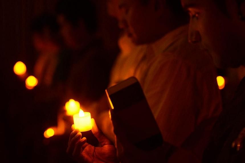People holding electric candles at the National Skin Centre Auditorium in memory of those who died from HIV and Aids during the 30th anniversary of the International Aids Candlelight Memorial, organised by Action for Aids Singapore in May 2013. -- PH