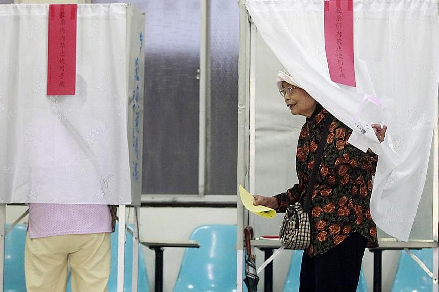 A woman walks out of a voting booth at a polling station during local elections in Taipei on Nov 29, 2014. -- PHOTO: REUTERS