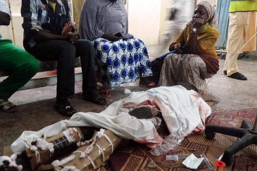 Relatives sit around one of the victims of twin suicide blasts at Kano central mosque in the accident and emergency ward of the Nassarawa Specialist Hospital in northern Nigeria's largest city of Kano on Nov 28, 2014.&nbsp;&nbsp;The Emir of Kano, Muh