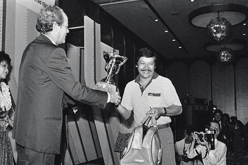 Ahmad Wartam, on behalf of his son Fandi Ahmad, receives the&nbsp;Footballer of the Year trophy at the annual Soccer Ball from then Law Minister E W Barker in 1982. -- PHOTO: ST FILE