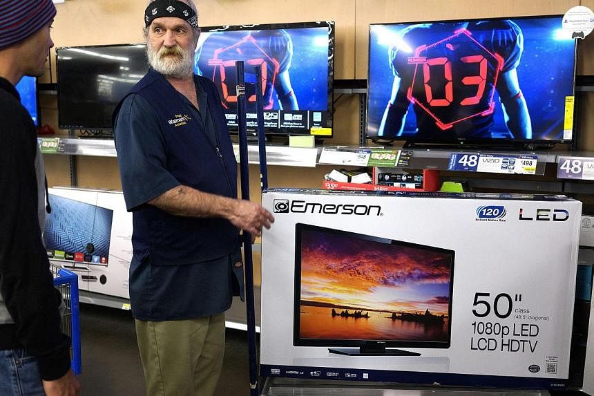A Walmart employee shows a customer (left) a 50-inch TV on sale for US$218 (S$284) on Black Friday in Broomfield, Colorado Nov 28, 2014. Black Friday, the biggest US shopping "holiday", kicked off with expectations that lower fuel prices and higher c