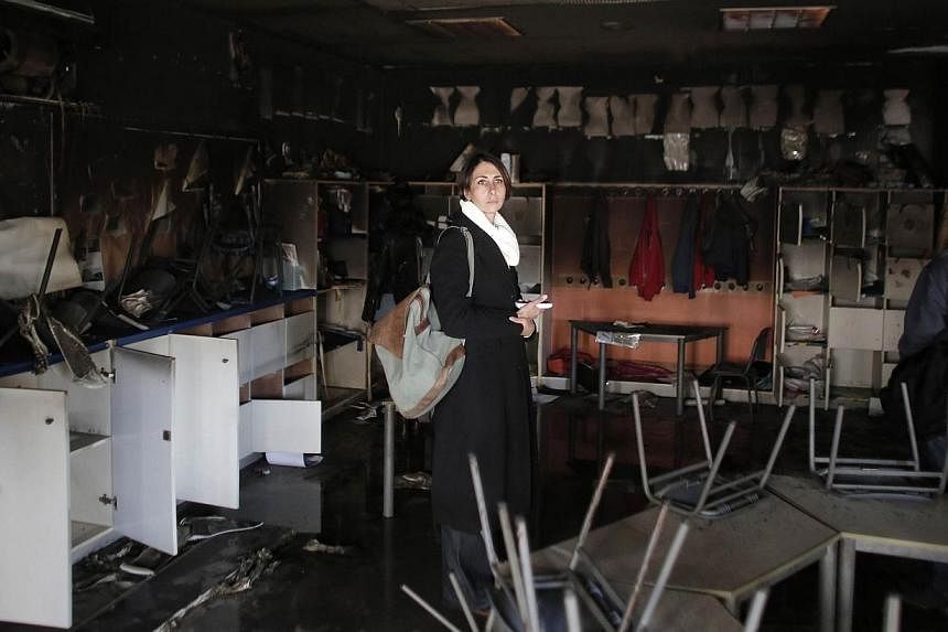 A woman inspects the damage on the aftermath of an arson attack that targeted first-grade classrooms at a Jewish-Arab school near the Arab neighborhood of Beit Safafa, in southern Jerusalem, on Nov 30, 2014.&nbsp;The attack sparked a wave of condemna