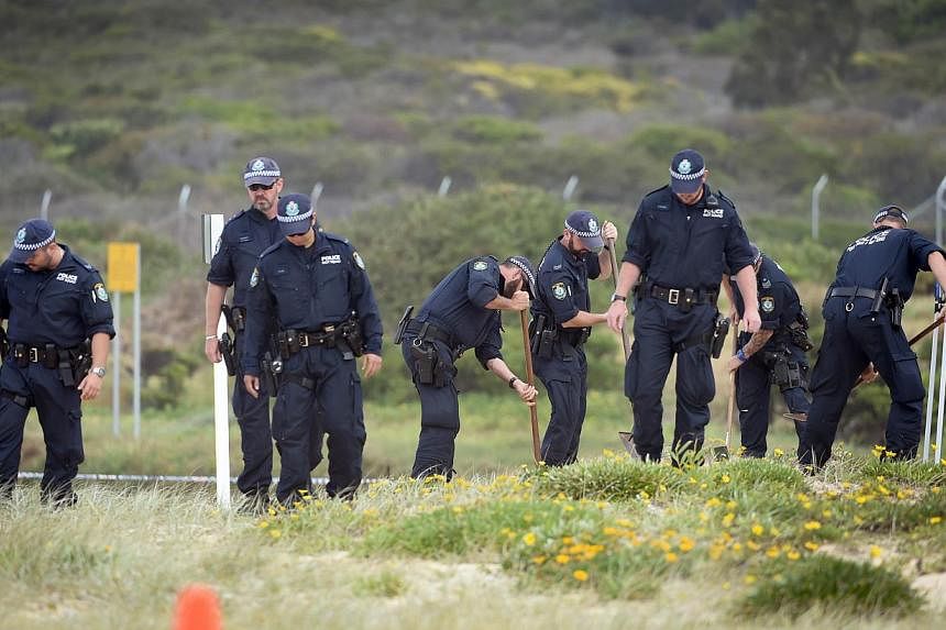 Police search the sand dunes after children playing at a Sydney beach on Nov 30, 2014, stumbled across the body of a baby buried under the sand. -- PHOTO: AFP