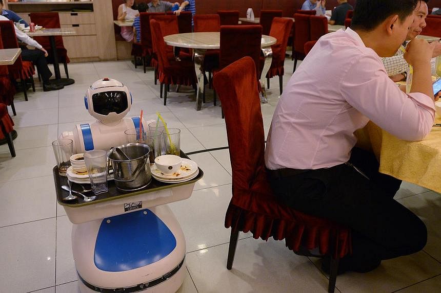 A flying robotic waiter served visitors at the National Productivity Month exhibition in Singapore last month while a robot (above) clears dishes at Supreme Tastes Jiang Nan Chun in Marina Square. -- PHOTO: NG SOR LUAN