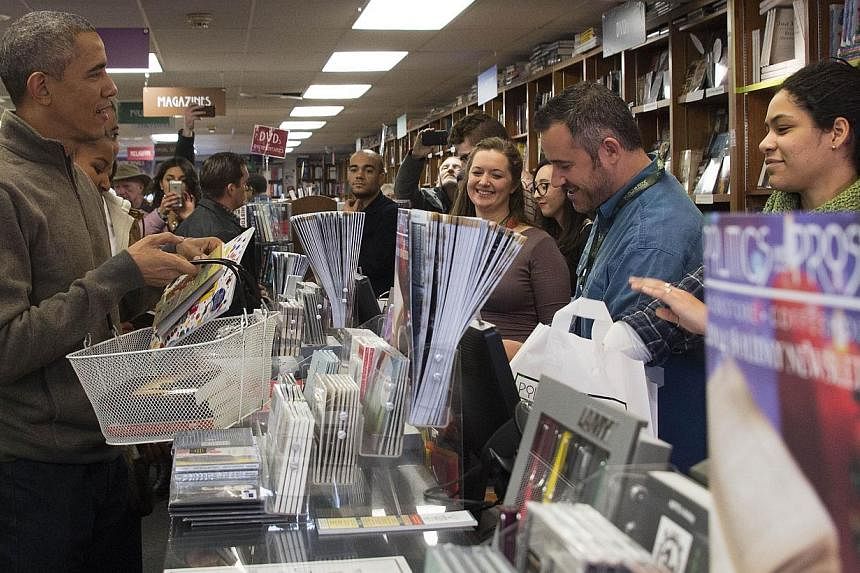 US President Barack Obama (left) shops at Politics and Prose bookstore, an independent bookseller, in Washington, DC, Nov 29, 2014. Accompanied by his teenage daughters Sasha and Malia, Obama bought 17 books.&nbsp;-- PHOTO: AFP&nbsp;