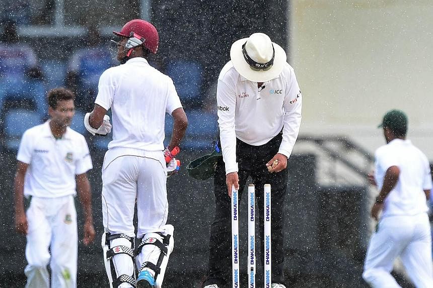 The umpire clears the wickets as players temporarily leave the field amid rain during a match between between the West Indies and Bangladesh on Sept 15, 2014. An umpire and former captain of Israel's national cricket team died on Saturday after being