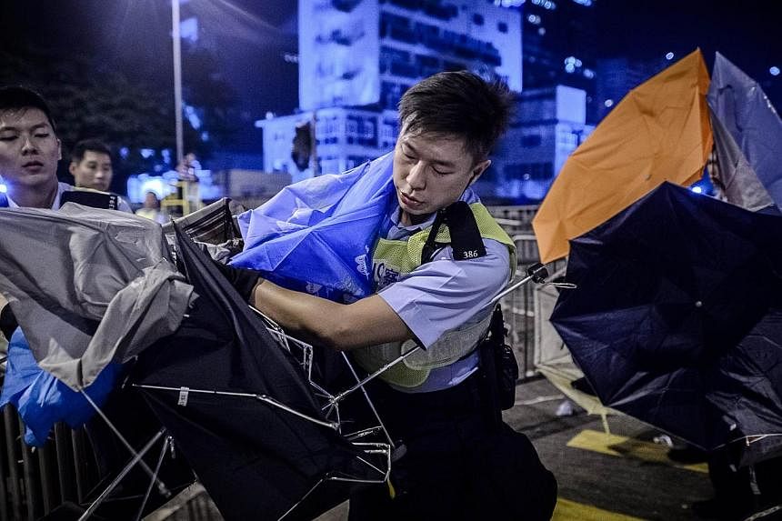 Policemen clear a road from umbrellas left behind during clashes with pro-democracy protesters outside the government headquarters in the Admiralty district of Hong Kong early Dec 1, 2014. -- PHOTO: AFP