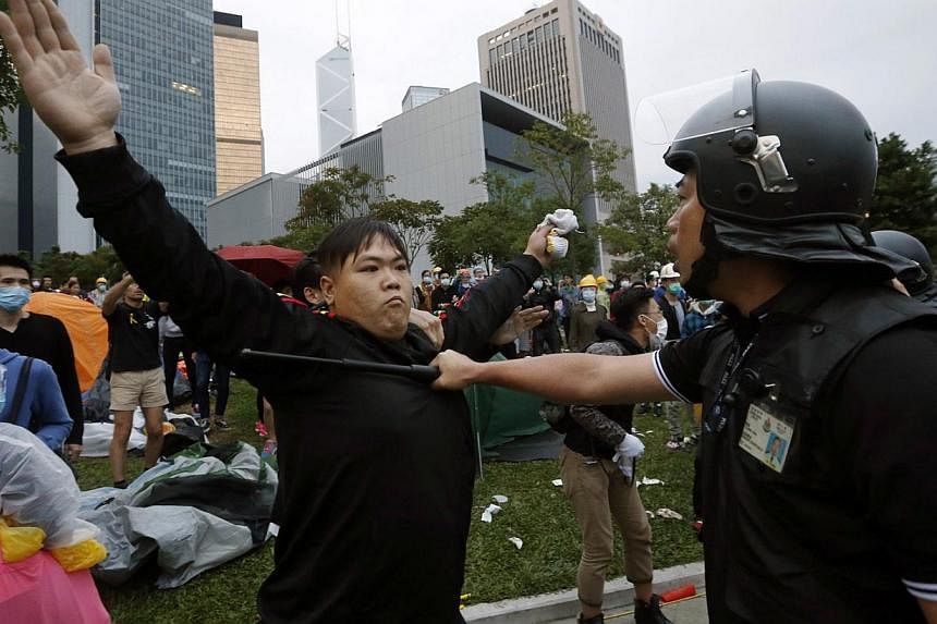 A pro-democracy protester blocks a riot policeman during a clash outside the government headquarters in Hong Kong Dec 1, 2014. Hong Kong police baton-charged and pepper-sprayed thousands of pro-democracy demonstrators in the early hours of Monday who