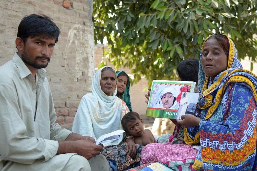 Villager Razia Shaikh holding up photos of her daughter, the victim of an honour killing, at an Agence France-Presse interview in Sukkur, Sindh province, on Oct 18. The family or community members who carry out such killings when a woman is declared 