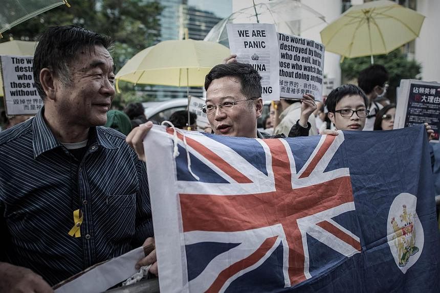 Pro-democracy protesters hold a Hong Kong colonial flag as they stage an occupy protest outside the British consulate in the Admiralty district of Hong Kong on Nov 21, 2014. -- PHOTO: AFP