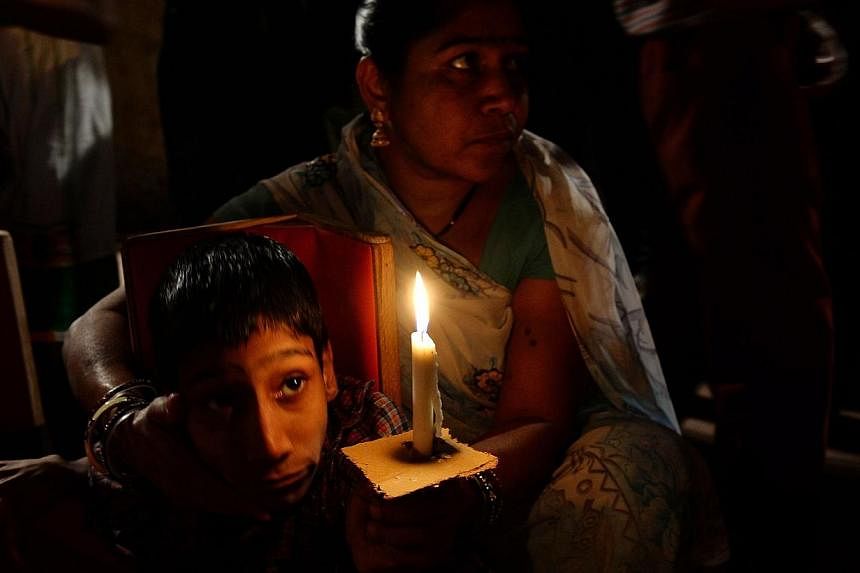 An Indian second-generation victim of the Bhopal gas disaster holds a candle during a vigil against the Union Carbide factory in Bhopal on Nov 30, 2014. -- PHOTO: AFP