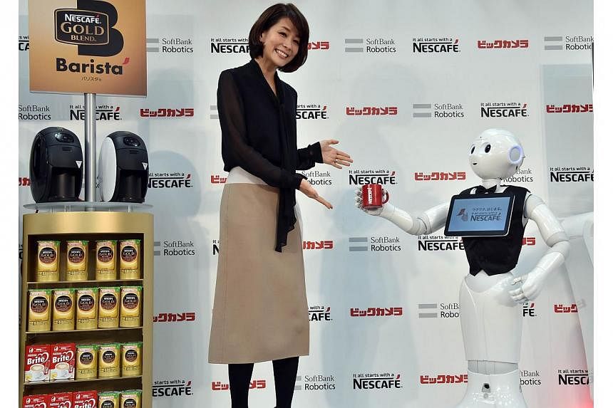 Japanese telecom giant Softbank's humanoid robot Pepper introduces Nestle's coffee machines at an electric shop in Tokyo on Dec 1, 2014. -- PHOTO: AFP&nbsp;