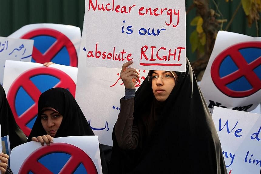 An Iranian student holds a placard reading "Nuclear energy is our absolute right" during a demonstration outside the Teheran Research Reactor in the capital Teheran on Nov 23, 2014, to show support to Iran's nuclear programme. -- PHOTO: AFP