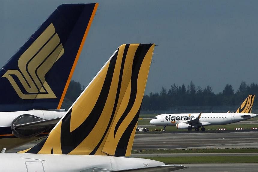 A Tiger Airways plane is towed on the runway past Singapore Airlines and Tiger Airways planes sitting on the tarmac at Changi Airport in Singapore. -- PHOTO: REUTERS&nbsp;