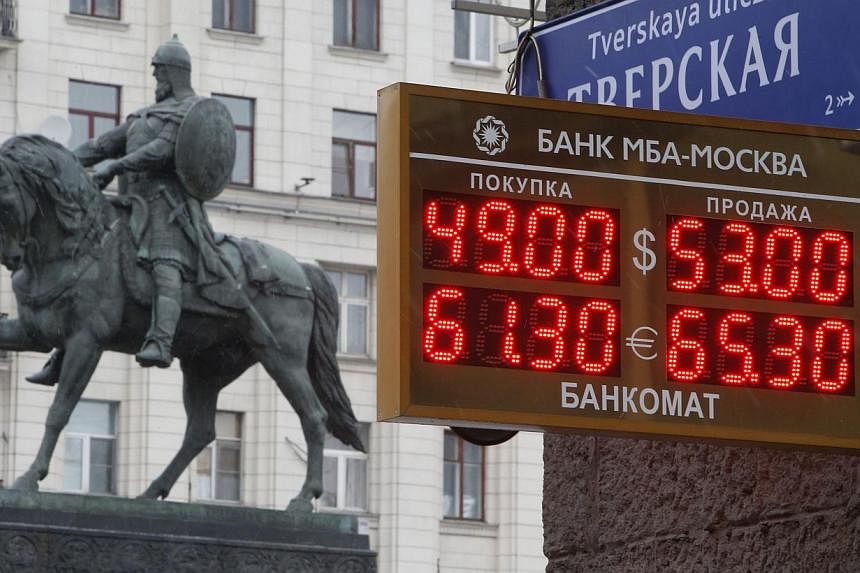 A board showing currency exchange rates, in front of a monument to Prince Yury Dolgoruky who founded Moscow in 1147, in the capital Moscow, on Dec 1, 2014. -- PHOTO: REUTERS