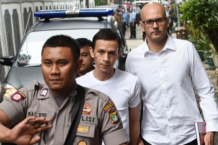 Canadian teacher Neil Bantleman (right) and co-accused teaching assistant Ferdinand Tjiong (centre) being escorted by a policeman as they arrive at the South Jakarta court in Jakarta on Dec 2, 2014. -- PHOTO: AFP