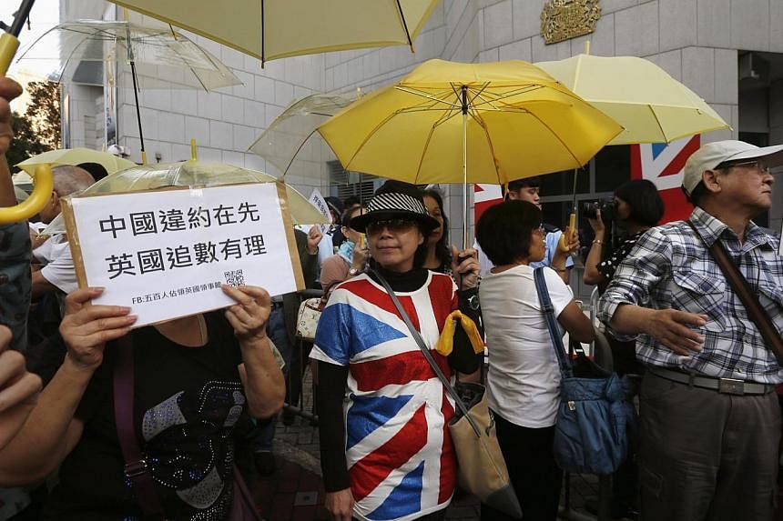 Pro-democracy protesters carrying yellow umbrellas, a symbol of the Occupy Central civil disobedience movement, demonstrate outside the British Consulate in Hong Kong on Nov 21, 2014.&nbsp;China rebuffed as "useless" on Tuesday complaints from Britis