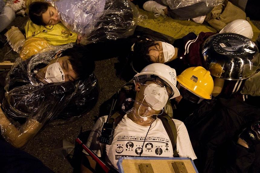 Pro-democracy protesters rest after clashes with police on an occupied road near the government headquarters in the Admiralty district of Hong Kong early on Dec 1, 2014.&nbsp;Hong Kong's pro-democracy occupation is entering its death throes with radi