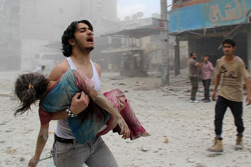A man carries a young girl who was injured in a reported barrel-bomb attack by government forces on June 3, 2014 in Kallaseh district in the northern city of Aleppo.&nbsp;Syria's civil war has killed more than 200,000 people in less than four years, 