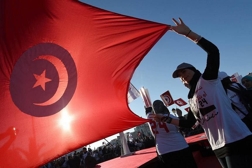 A supporter of Moncef Marzouki, the current Tunisian president who is defending his position in the upcoming presidential elections holds up her national flag during a campaign rally on Nov 19, 2014, in Bizerte, north-east of Tunis.&nbsp;Tunisia's ne