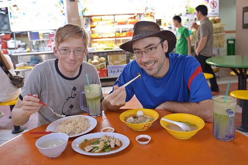 Two French men, Killian Blais (with hat), 31 and William Kohler, 31, tucking in local food at Maxwell Road Food Centre on Dec 1, 2014. -- ST PHOTO: LIM SIN THAI