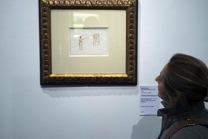 A woman in Paris looks at a watercolour from Antoine de Saint-Exupery showing the Turkish astronomer who discover the planet of The Little Prince. The painting valued between 400 000 and 500 000 euros will be auctioned next December 9. -- PHOTO: AFP