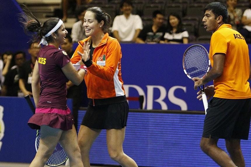 Team Micromax Indian Aces' Ana Ivanovic (centre) of Serbia celebrates with teammates Sania Mirza (left) and Rohan Bopanna of India after their mixed doubles match against UAE Royals at the International Premier Tennis League (IPTL) in Singapore on De