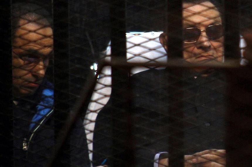 Egypt's former president Hosni Mubarak (right) and his son Gamal sit behind bars during a court hearing on Nov 29, 2014 in the capital Cairo. Egypt's public prosecutor appealed on Tuesday against a court decision last Friday to drop charges against M