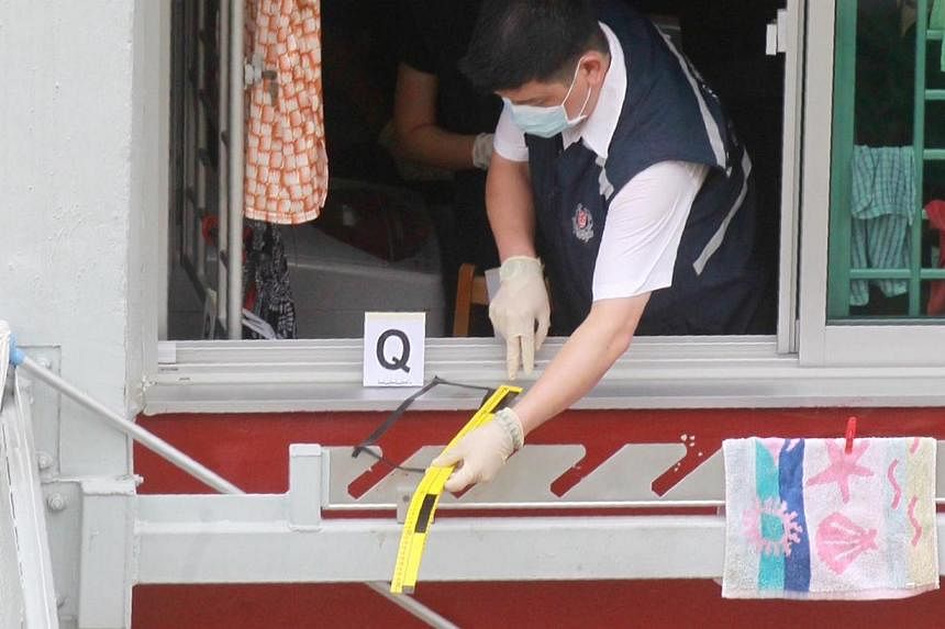 A police investigator at the kitchen window of the sixth-floor unit at Block 105 in Ang Mo Kio Avenue 4 where the dismembered body of Andrea Tay Su Lin was found at the foot of the same block on the morning of June 4, 2014. -- PHOTO: SHIN MIN